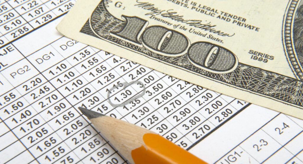 $100 bill and pencil on bet slip $100 bill and pencil on bet slip