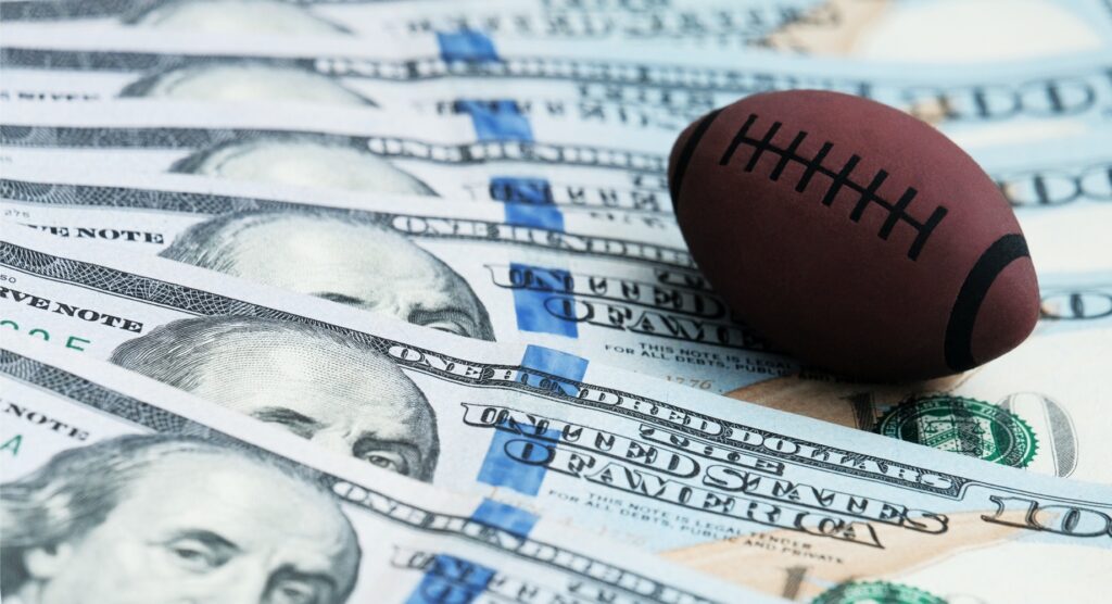 American football toy on spread of $100 bills