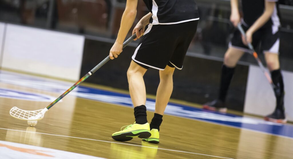 Male floorball player controlling ball on court