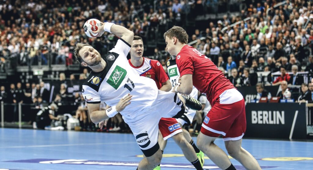 Handball player taking shot while being tackled