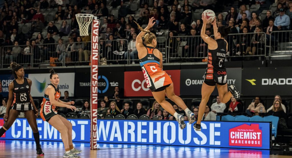 Player shooting mid-air during a women's netball match