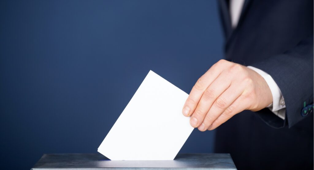 Male sliding voting slip into ballot box
