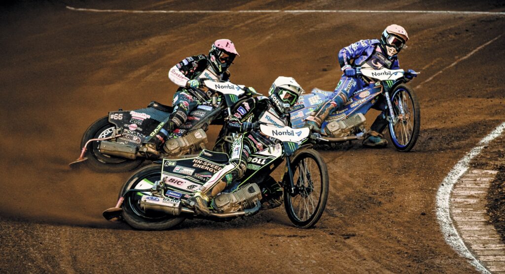 Three speedway racers sliding around bend Three speedway racers sliding around bend