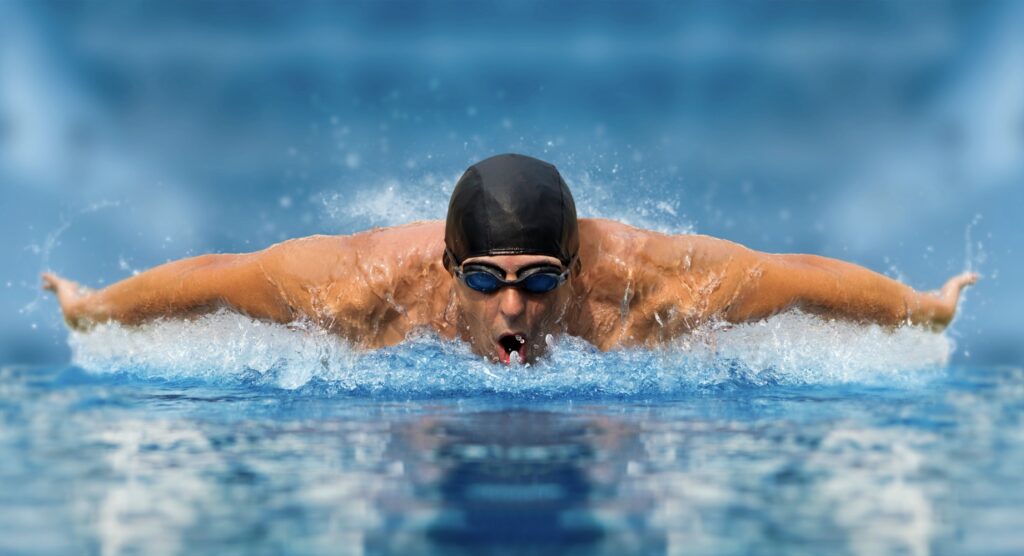 Male swimming competing during race