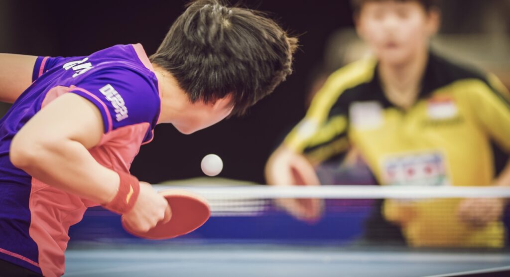 Rear view of player serving during table tennis match