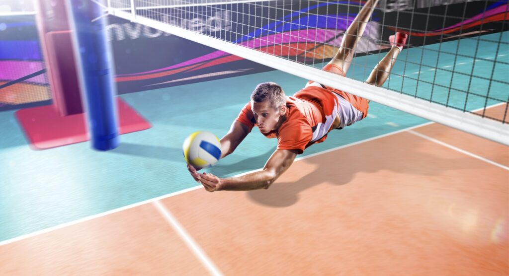 Male volleyball player diving to hit ball