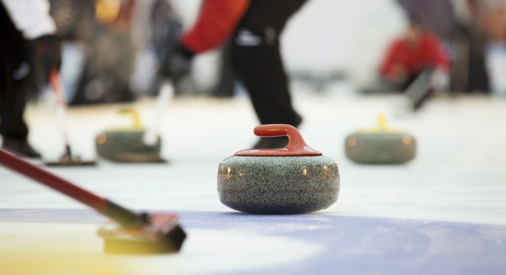 View of curling stones and players from house during a match