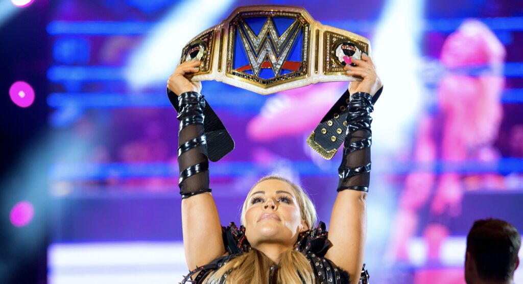 Female wrestler raising championship belt above head