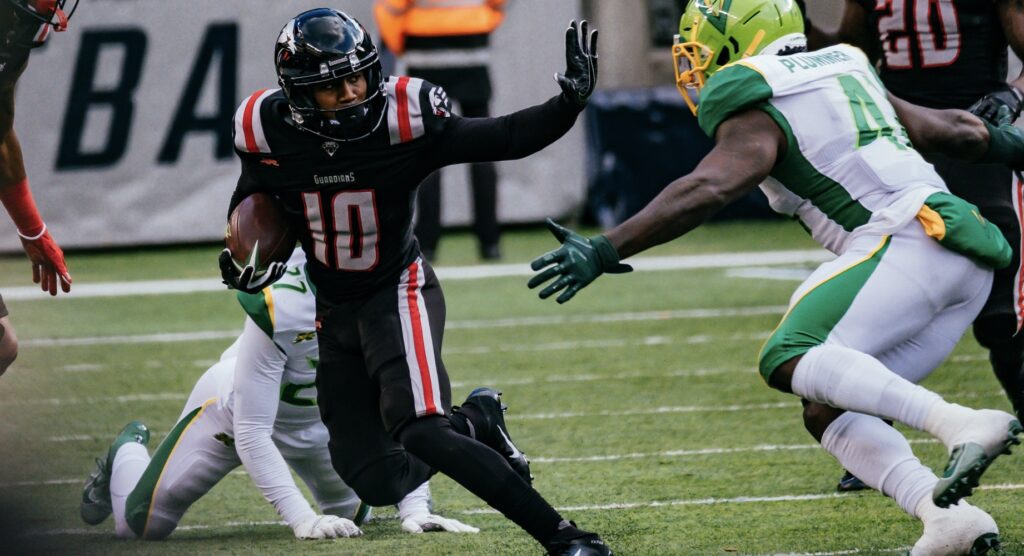 XFL player running with ball as opponent prepares to make tackle