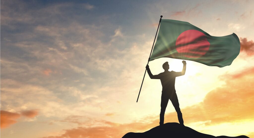 Man waving Bangladesh flag against the sunset