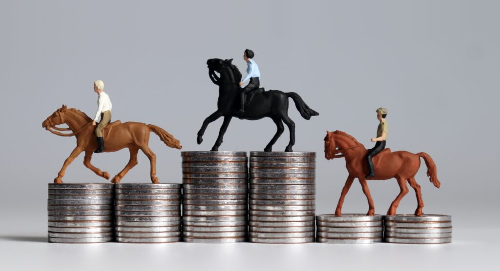 Three miniature horses on stacks of coins