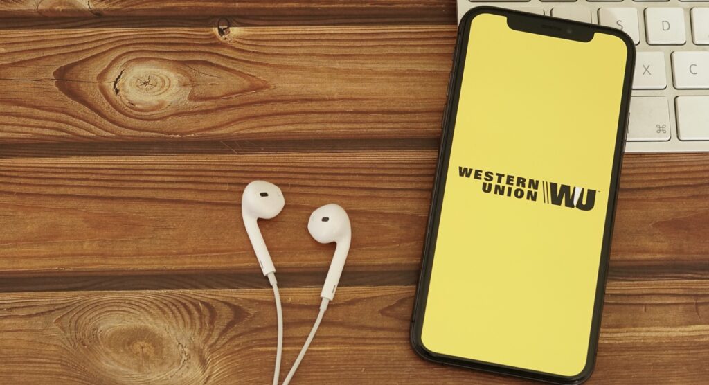 Western Union logo on smartphone beside earphones