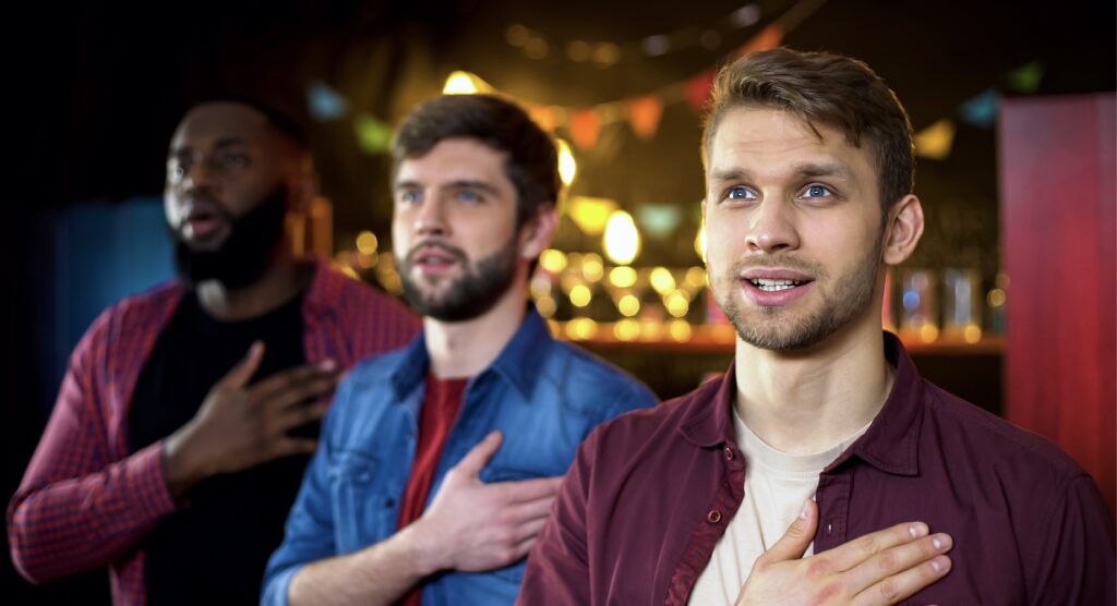 Three males singing national anthem