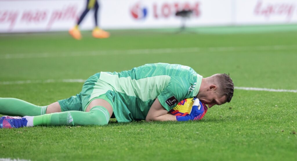 Goalkeeper holding ball on ground