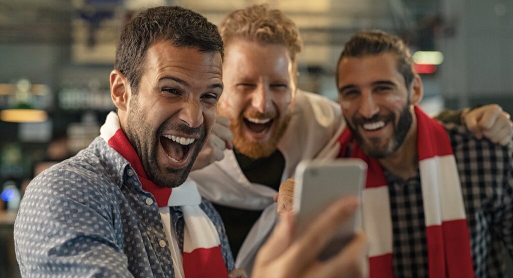 Three males celebrating winning mobile bet