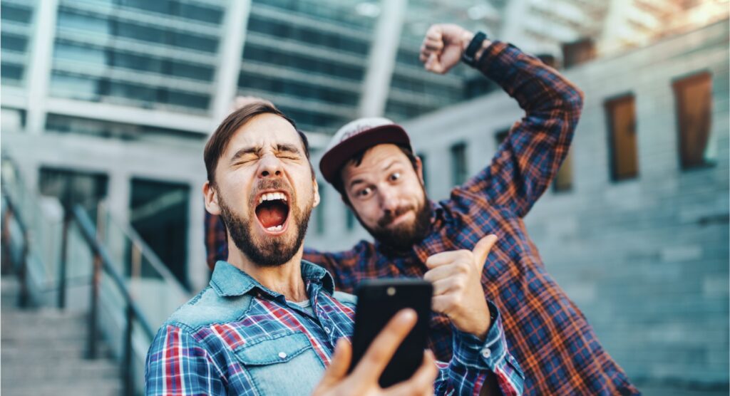 Two friends celebrating winning mobile bet