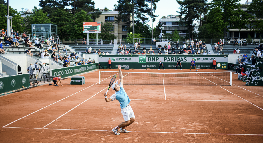 A tennis player serving on the clay pitch at Roland Garros 