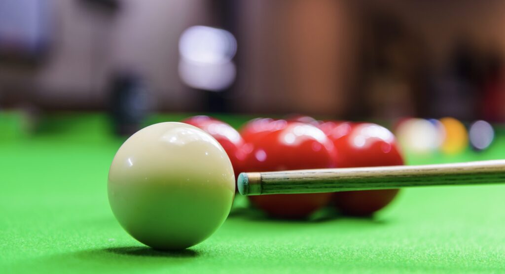 A snooker table with balls, cue and chalk Tip of snooker cue about to connect with white ball
