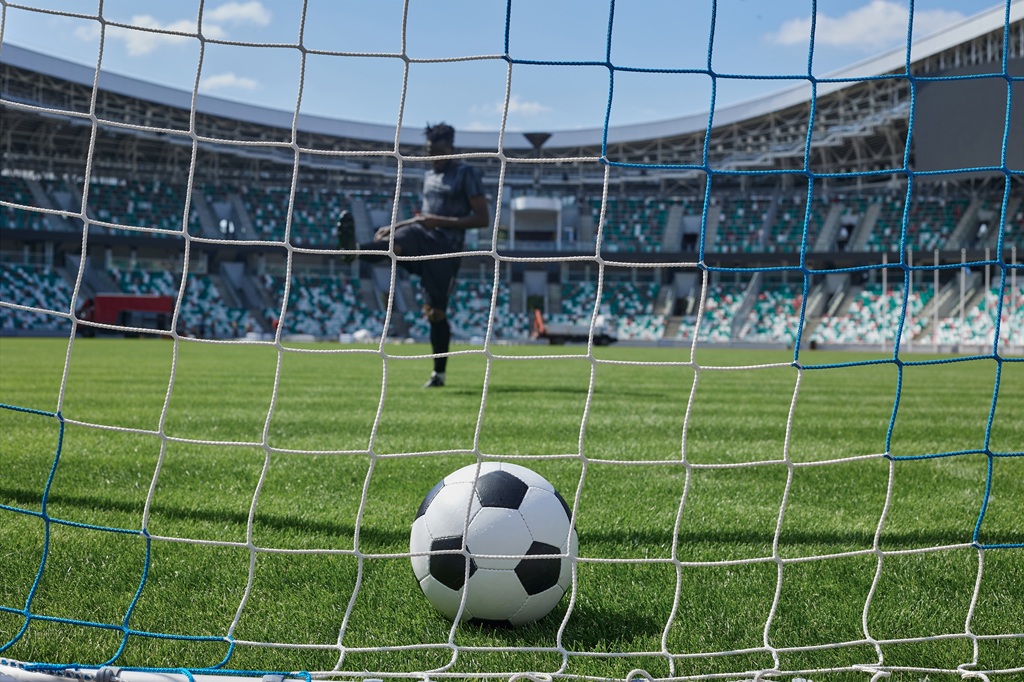 Soccer player kicks the ball into the goal at the stadium