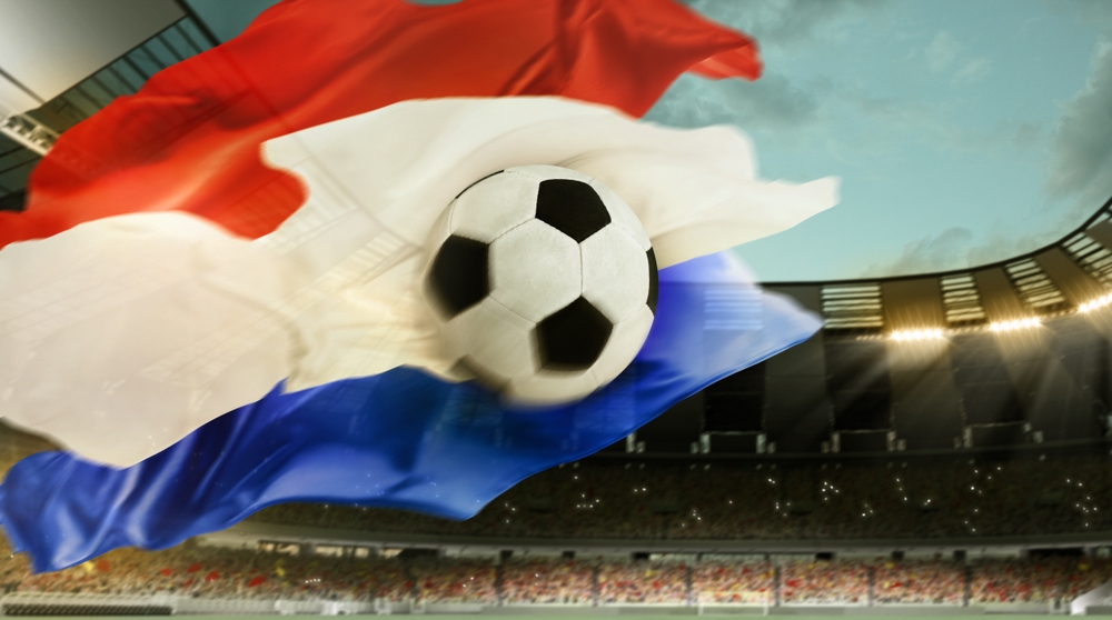 een voetbal tegen een Nederlandse vlag