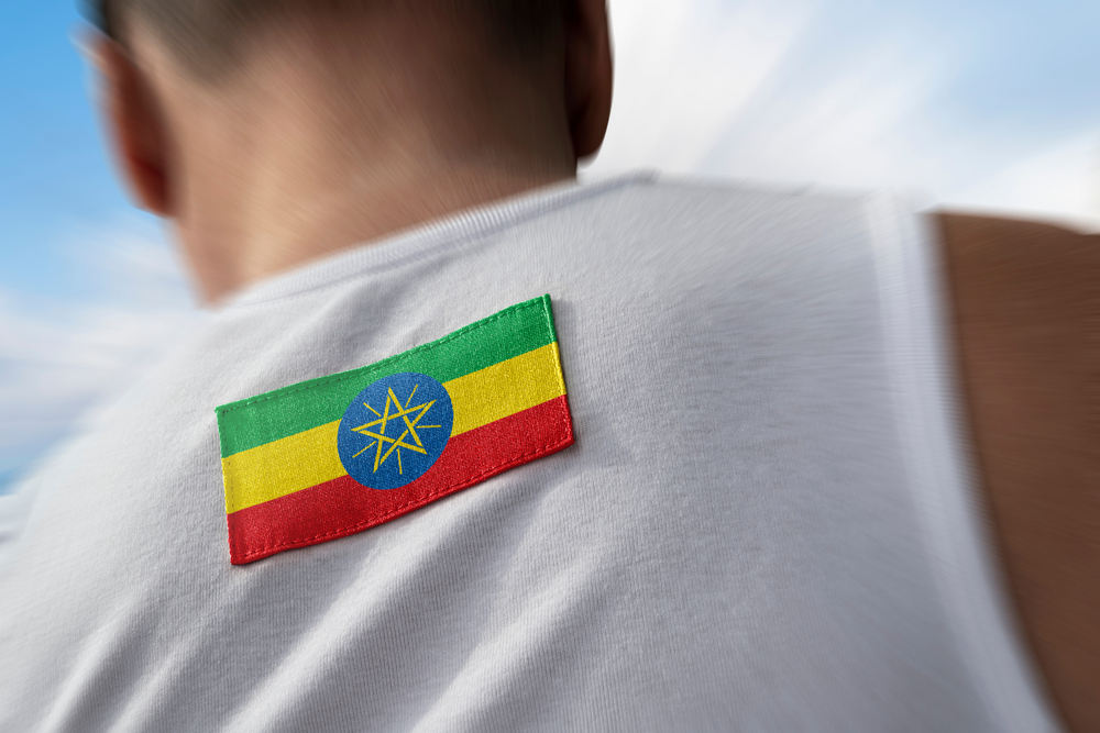 Ethiopian flag patch on the shoulder of an athlete's white vest, viewed from behind
