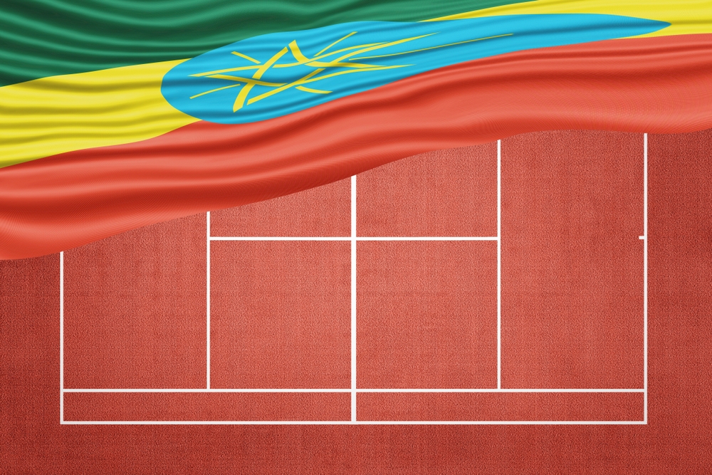 Ethiopian flag draped above a clay tennis court surface with white court markings