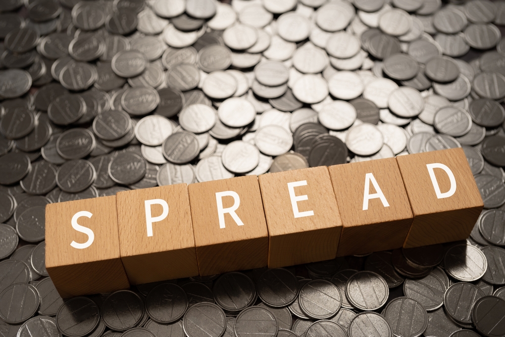 Wooden blocks spelling SPREAD on scattered coins Wooden blocks spelling SPREAD resting on a pile of coins