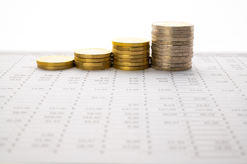 Four ascending stacks of euro coins resting on a printed financial spreadsheet