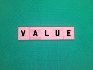 Pink letter tiles spelling VALUE on a green background