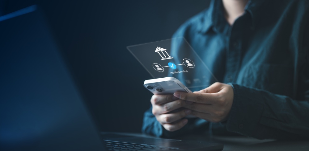 Mobile banking transfer on a smartphone Person using a smartphone with a mobile banking graphic showing a bank icon and secure transfer symbols