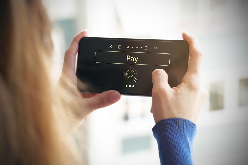 Searching for payment options on a smartphone Person holding a smartphone showing a search box with the word Pay entered
