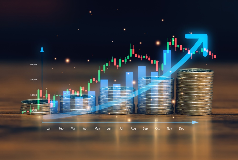 Rising stacks of coins iun front of a glowing financial chart